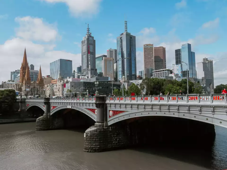 The image depicts the skyline of Melbourne, Australia. Prominent modern skyscrapers are visible in the background, showcasing the city's architectural diversity.